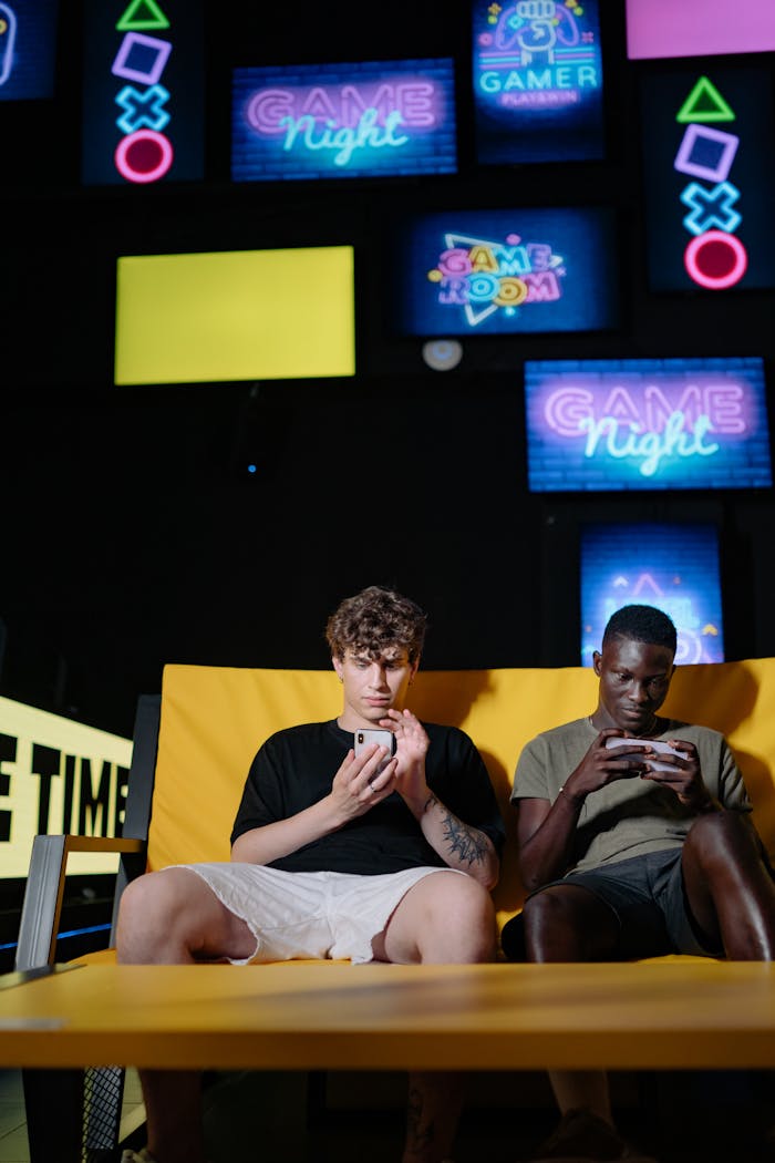 Two young men intensely focused on mobile gaming during a vibrant game night.